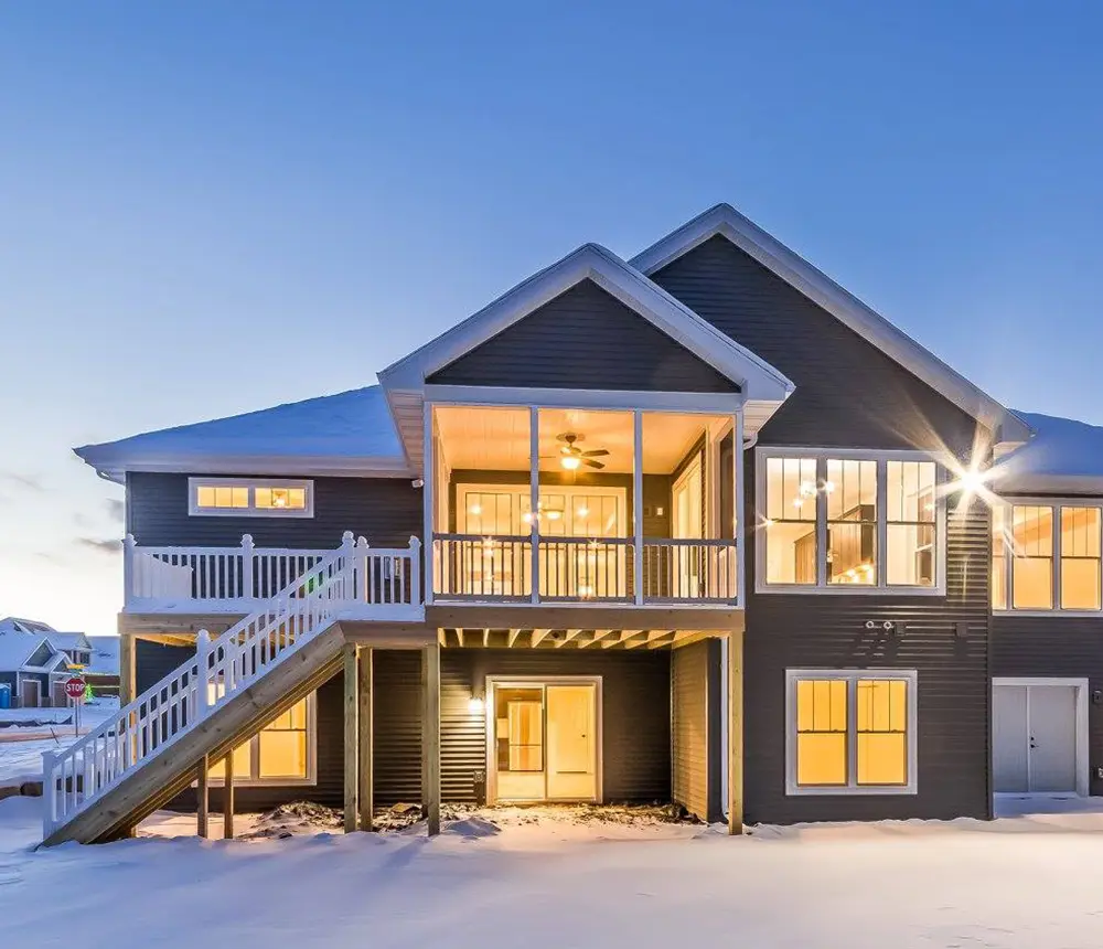 An elevated deck attached to a large home covered in snow