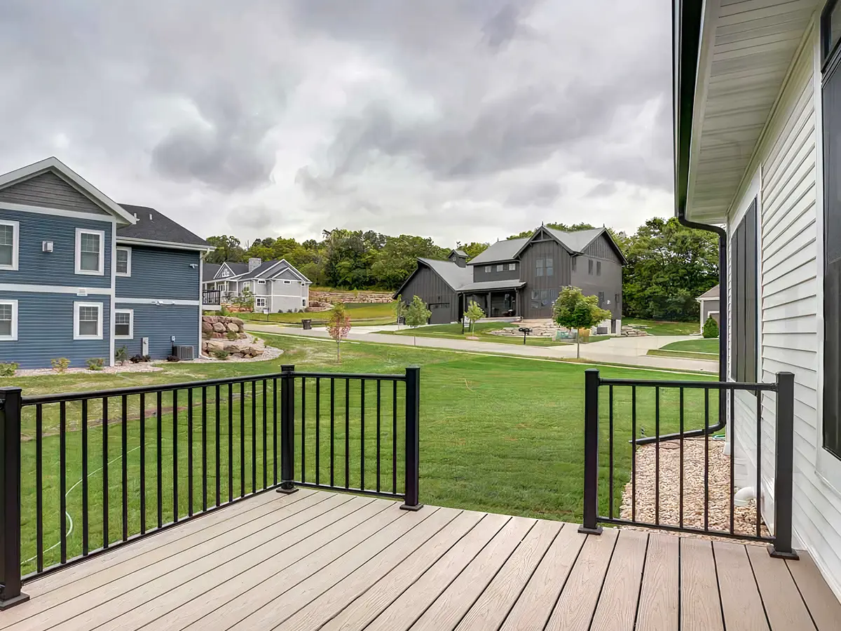 Composite decking with black metal railing and a large lawn