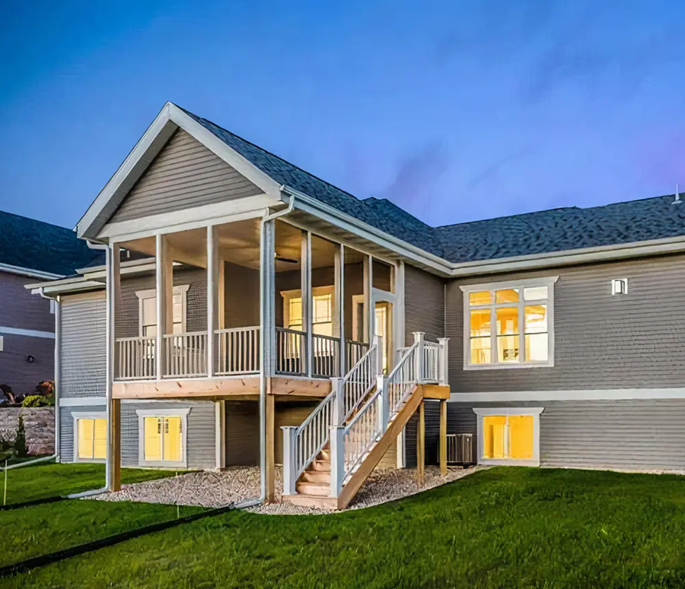 An elevated deck with white metal railing attached to a house with gray siding