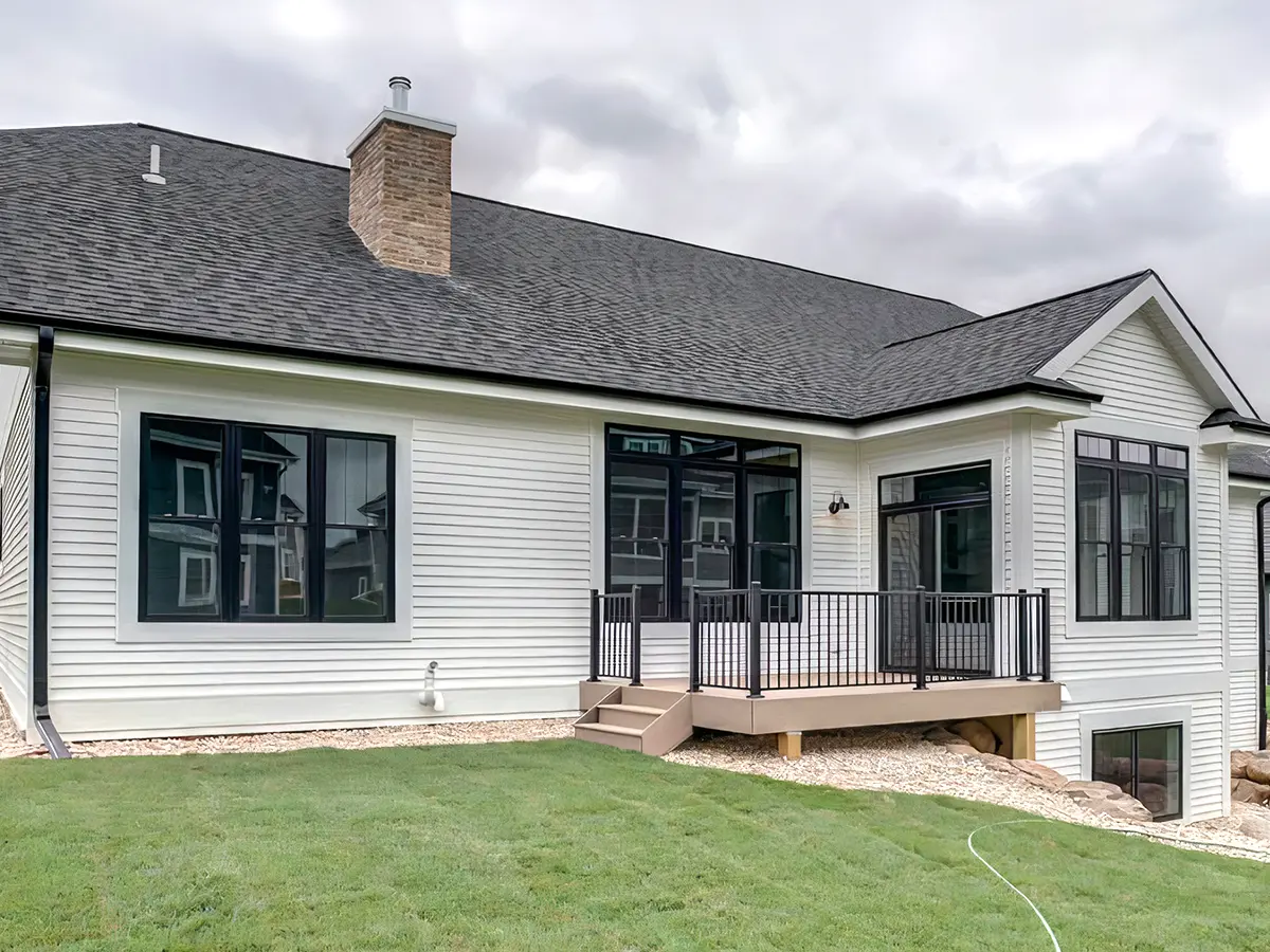 Large home with white siding and asphalt shingles on roof with a small composite deck with metal railing