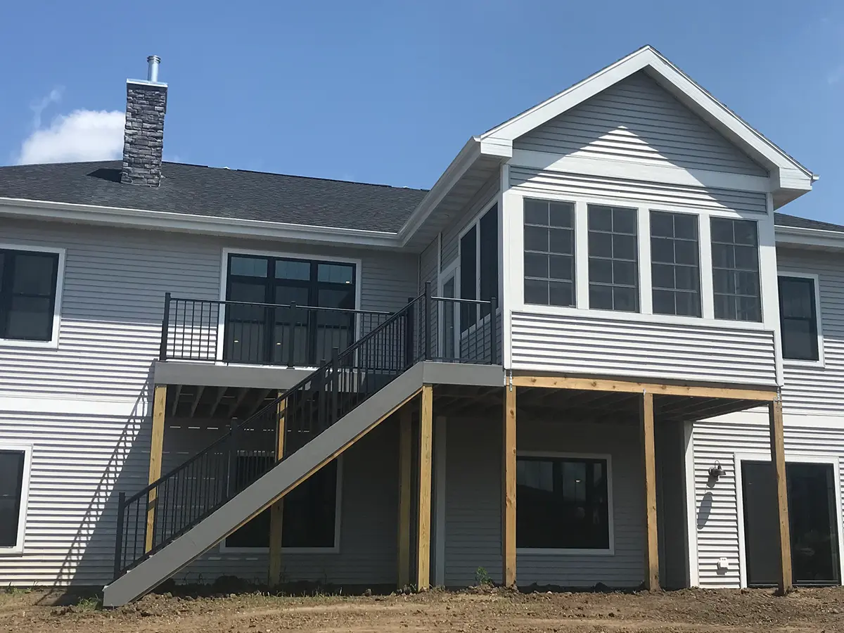 A home with large windows with an elevated deck with black metal railing