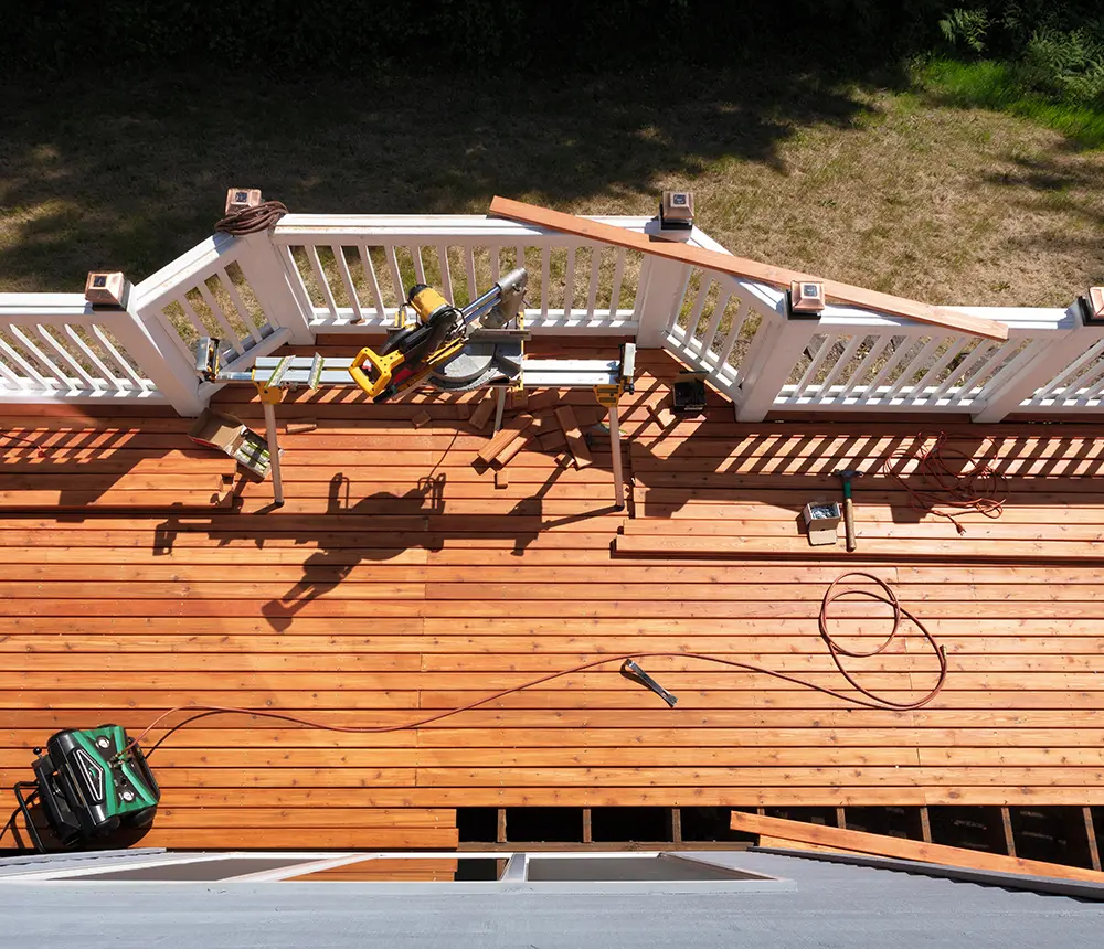 Cedar decking boards installation on a deck with white metal railings