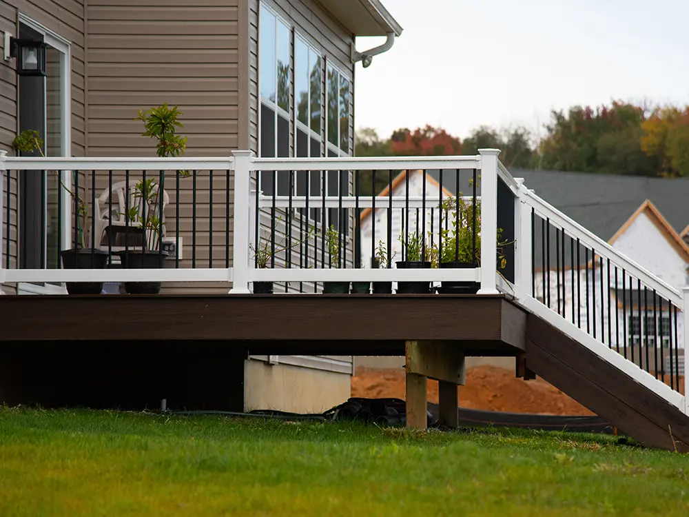 An elevated deck with plants on it, with a set of stairs and a beautiful railing