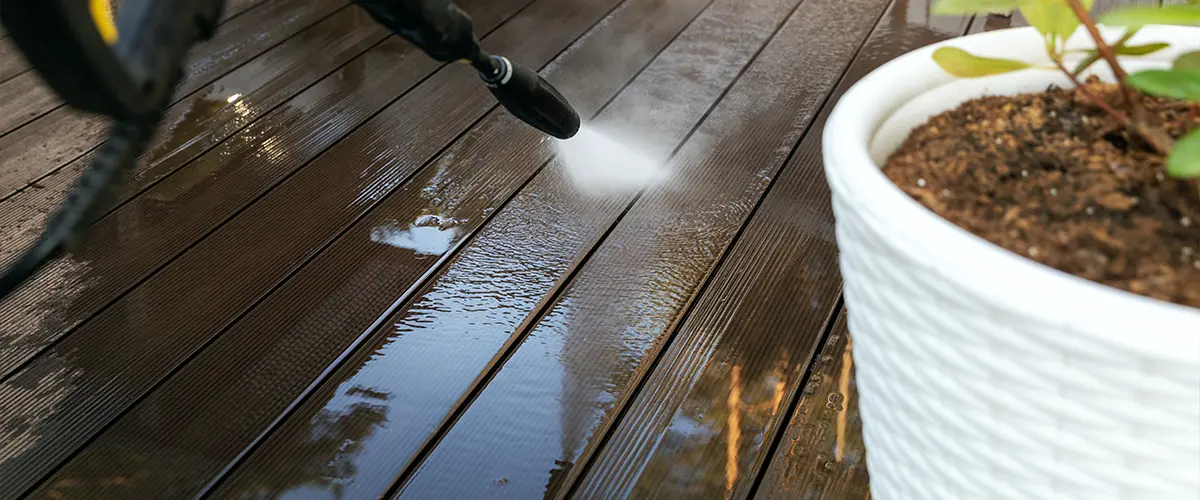 Pressure washing a deck with a potted plant near it